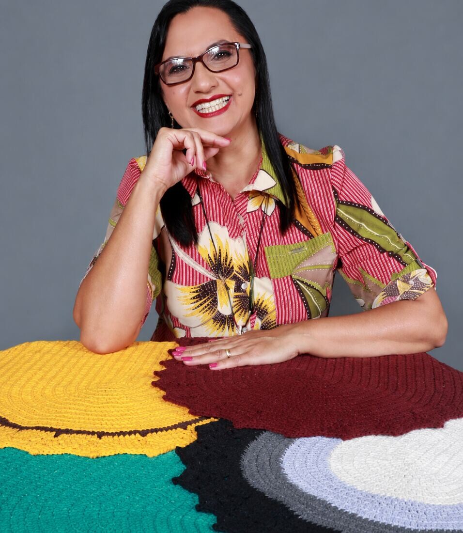 Marina Costa, artesã especialista em crochê, segurando peça de crochê com as cores do Brasil